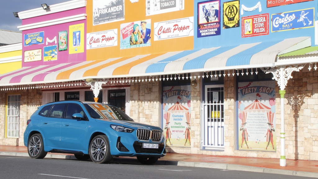 A blue BMW iX1 EV against a colourful backdrop.