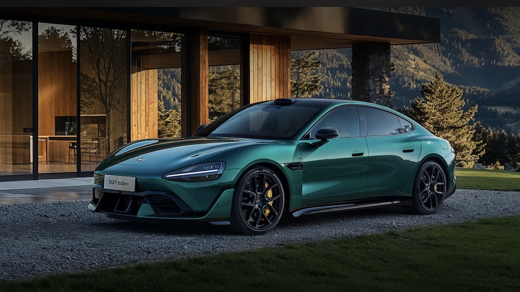 A Xiaomi SU7 Ultra in British Racing Green pictured in a scenic outdoor setting with a modernist home in the background. 