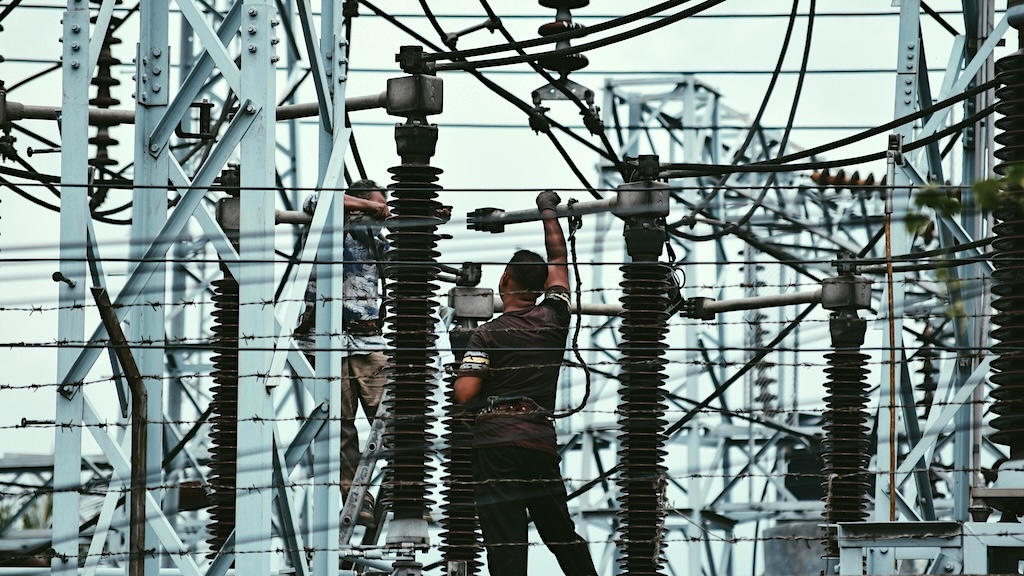 Two men working on a high-voltage substation