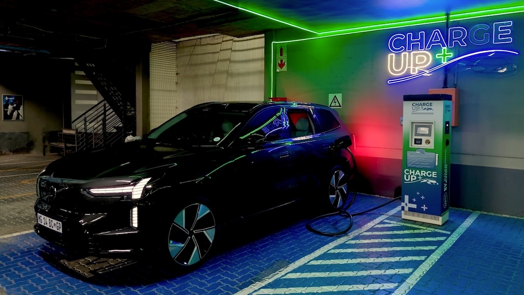 A black Volvo EX90 at night: plugged in and charging