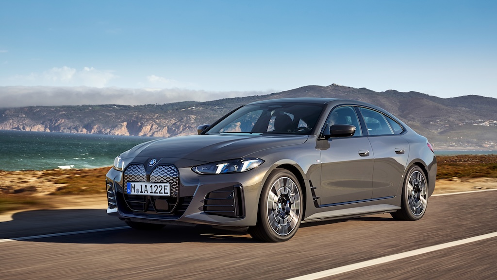 A grey-ish BMW i4 M60 xDrive driving along the ocean