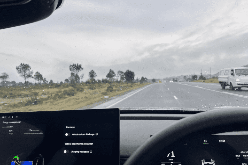 Driver's perspective from inside the cabin, showcasing the crisp central infotainment touchscreen and digital instrumentation on the open road.