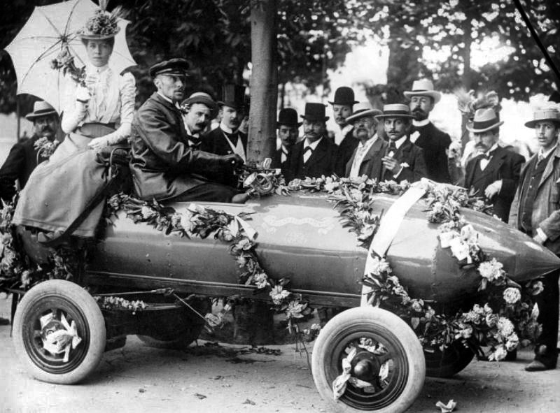 Jenatzy sits in his electric car, surrounded by a crowd after breaking the world speed record in 1899.