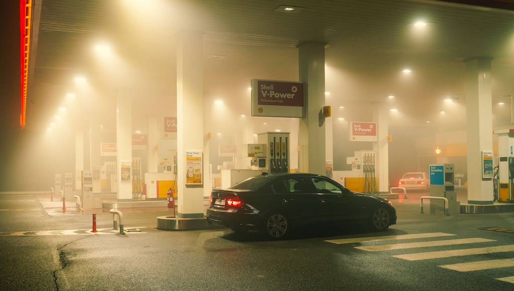 A BMW sedan filling up at a Shell service station at night.